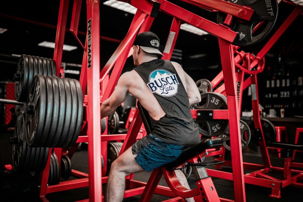 man in gray t-shirt and blue denim jeans sitting on red metal bar